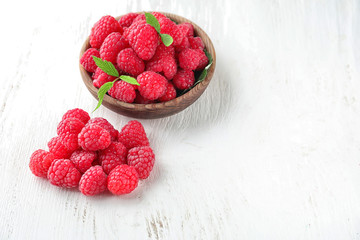Ripe aromatic raspberries on white wooden background