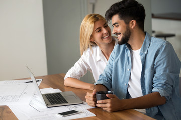 Photo of cheerful loving young couple using laptop