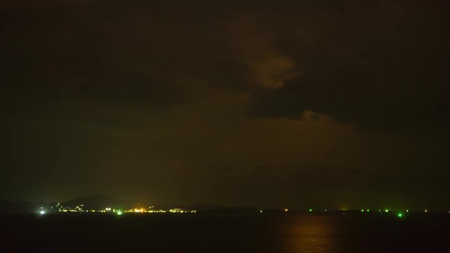Timelapse of dramatic panorama of big bright scary moon at sea in Thailand. Mysterious moon and dark clouds moving across sky leaving reflexes on water. Halloween mood in the air