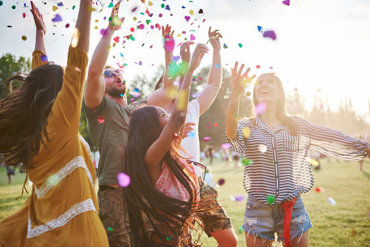 Five young adult friends throwing confetti mid air at Holi Festival