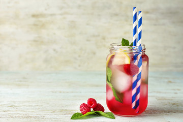 Glass jar with fresh raspberry mojito on table