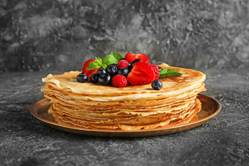 Plate with tasty pancakes and berries on grunge background