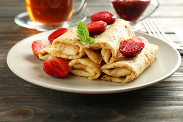 Plate with tasty pancakes and berries on wooden table