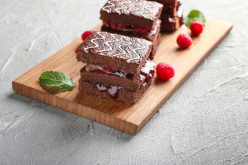 Board with tasty chocolate cakes and raspberry jam on light table