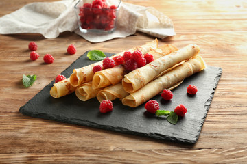 Slate plate with tasty pancakes and berries on wooden table