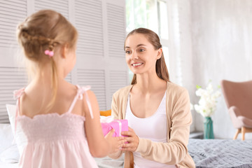 Cute little girl giving her mom gift box for Mother's Day at home