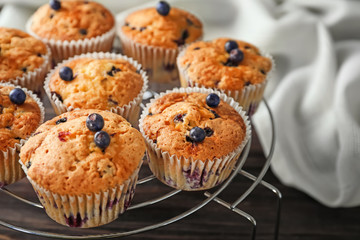 Cooling rack with tasty blueberry muffins on wooden table, closeup