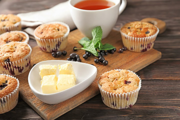 Tasty blueberry muffins with butter on table