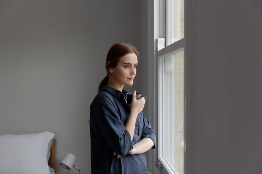 Portrait of woman having coffee by window