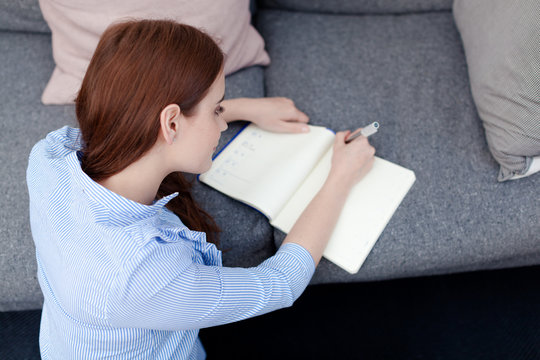 Woman sitting on floor writing in notepad