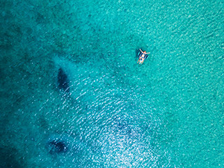 Aerial view of woman floating on the water mattress in the turquoise sea