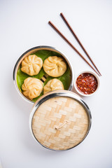 Traditional dumpling momos food from Nepal served with tomato chutney over moody background. Selective focus