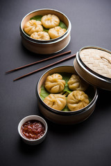 Traditional dumpling momos food from Nepal served with tomato chutney over moody background. Selective focus