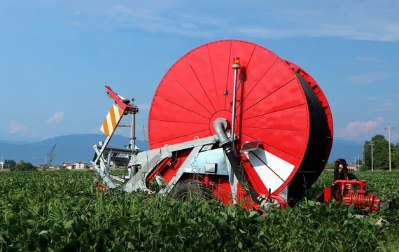 Brand new red hose reel irrigation machine for agriculture on a plantation  in summer