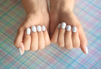Female hands with stylish nails on color paper, closeup