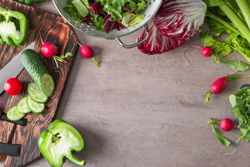 Cutting board with ingredients for vegetable salad on grey background