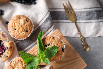 Wooden board with tasty blueberry muffins on grey table