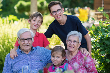 Grandparents with their grandchildren in the garden in summer