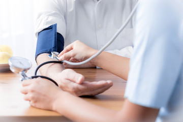Close-up of nurse with stethoscope checking blood pressure of senior person - obrazy, fototapety, plakaty