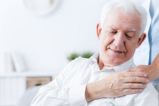 Close-up of senior man touching hand of friendly caregiver