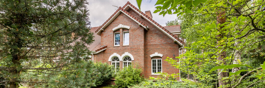English residence with red brick wall and windows in the forest. Real photo