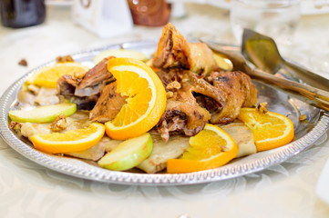 Fried chicken with orange and apples slices is on the platter.