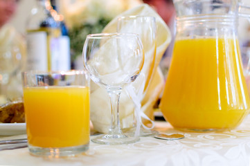 A glass decanter and a glass of orange juice are on the table.