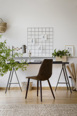 Minimalist drawings pinned to an organizer on a white wall in a stylish home office interior for an artist