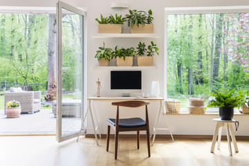 Zen home office with computer in a beautiful, spacious living room interior with plants and an...