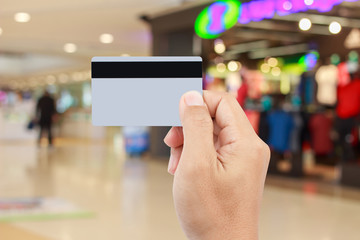 Man hand holding credit card on blur of shopping mall with shining bokeh lights for credit card payment concept