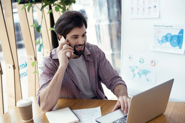 Man sitting at the table at creative stylish office talking on p