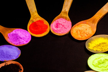 colourful powder paint on black fabric. colourful powder paint in wooden spoon on black fabric in black background with copy space. powder paint is a natural color that humans use.
