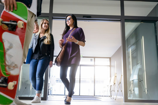 Students entering college building by glass doors