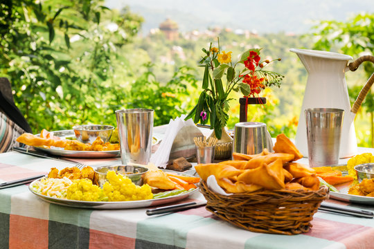 Traditional Indian-Nepali lunch dish with spice vegetables, raw greens, mutton curry and salad, served with fried bread sticks, in a terrace overlooking Nuwakot, Nepal.