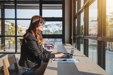 Young asian businesswoman using laptop computer work at the coffee shop.