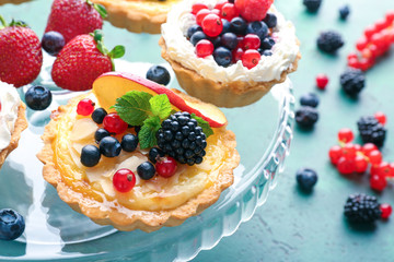 Tasty tartlets with berries on dessert stand, closeup