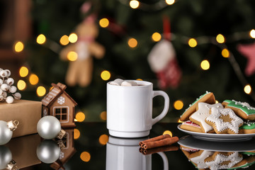 Obraz na płótnie Canvas Cup of delicious hot cocoa with cookies and Christmas decorations on table against blurred lights