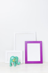 Wooden empty frames for a photo and wooden emerald pineapple on a background of a white wall. Blank paper frames, modern home decor mock-up. Interior accessories, home decor elements.