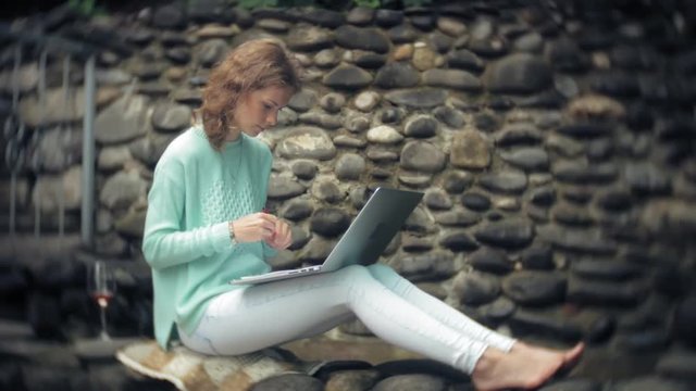 Woman with laptop and documents on the background of a stonewall wall