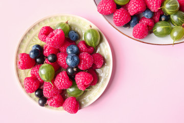 Plates with delicious ripe berries on color background