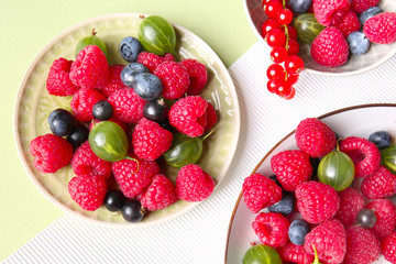 Plates with delicious ripe berries on color background