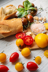 Fresh cherry tomatoes and bread on white wooden table