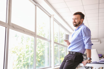 Handsome businessman drinking coffee in office