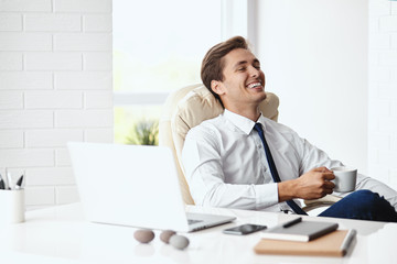Fototapeta premium Young handsome businessman smiling in a modern office