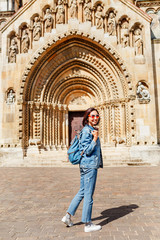 Fototapeta na wymiar Mixed race woman traveler with backpack admiring tourist sights and destinations in Europe. Jaki chapel in Vajdahunyad castle in Budapest