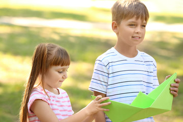 Cute little children playing with paper ship outdoors