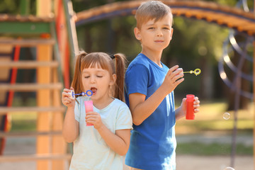 Cute little children blowing soap bubbles outdoors