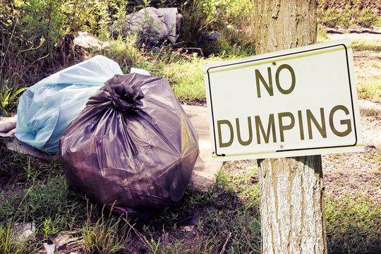 Illegal dumping in the nature with "No Dumping" sign indicating in the countryside - concept image