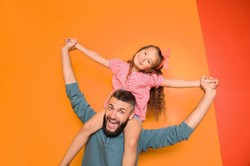 Funny portrait of father and his little daughter on color background