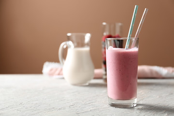 Glass with tasty raspberry milkshake on wooden table
